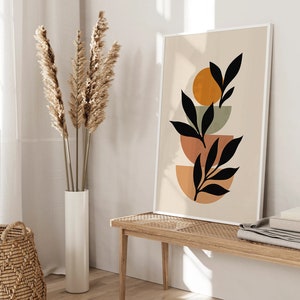 Op de afbeelding: Abstracte kunstprint met een gestileerd zwart bladontwerp op een beige achtergrond. Het blad is gelaagd over drie overlappende cirkels in tinten oranje, bruin en groen.