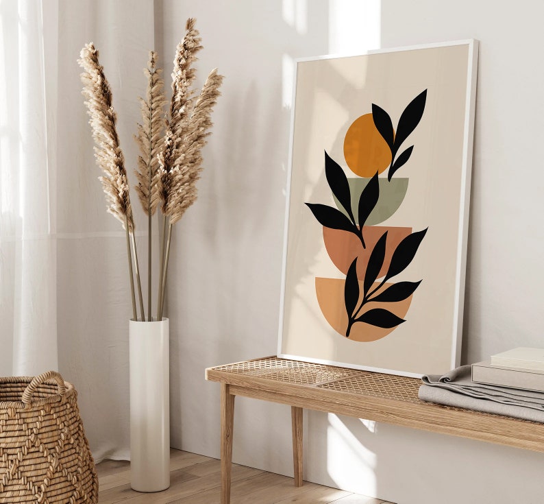Op de afbeelding: Abstracte kunstprint met een gestileerd zwart bladontwerp op een beige achtergrond. Het blad is gelaagd over drie overlappende cirkels in tinten oranje, bruin en groen.