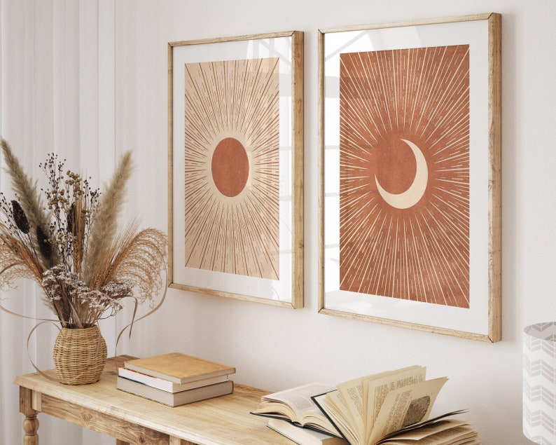 Puede incluir: Dos impresiones enmarcadas con un dise&ntilde;o minimalista. Las impresiones presentan un sol y una luna creciente con l&iacute;neas radiantes de color naranja quemado sobre un fondo crema.