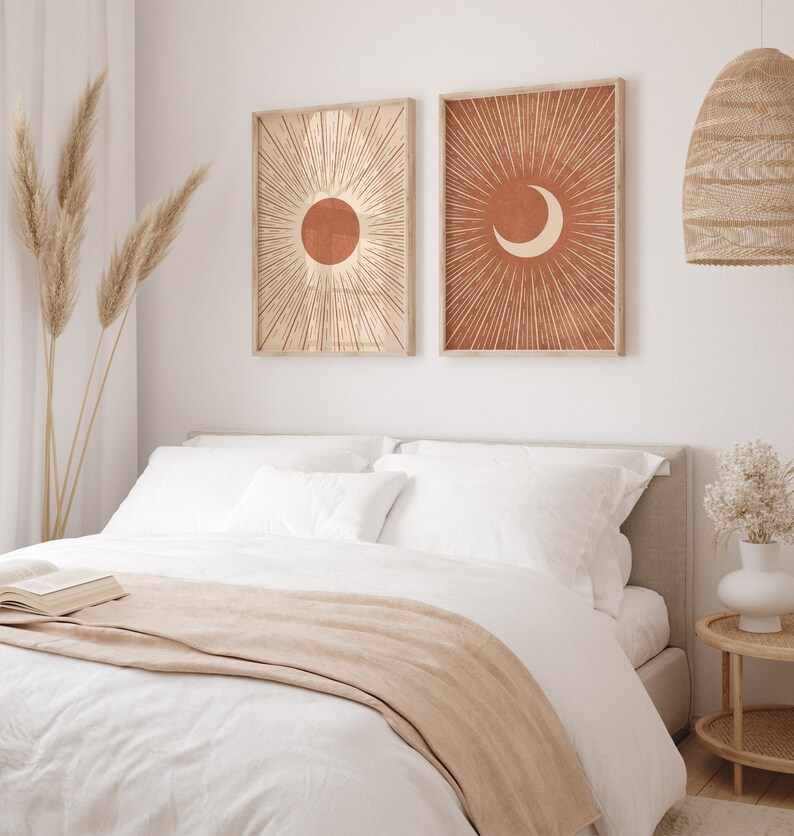 Puede incluir: Dos impresiones enmarcadas con un dise&ntilde;o minimalista. Las impresiones presentan un sol y una luna creciente sobre un fondo terracota con l&iacute;neas blancas que irradian hacia afuera.