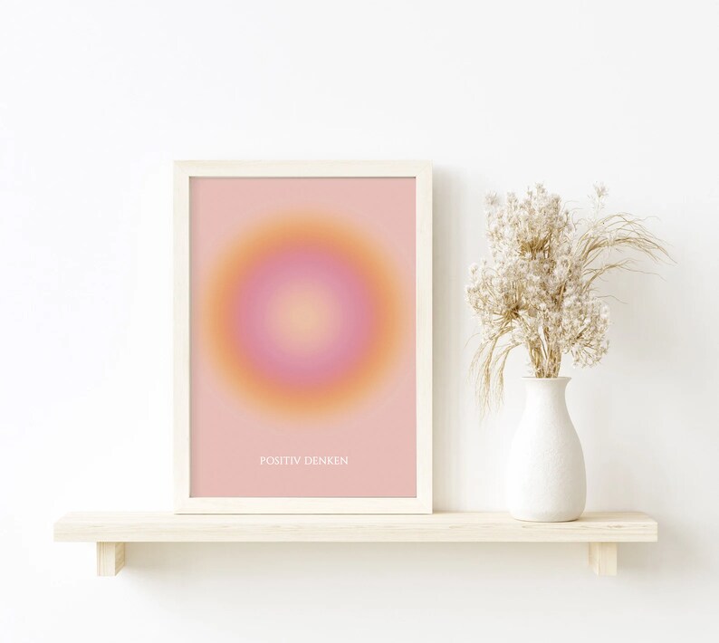 May include: A framed print with a pink and orange gradient circle in the center. The text "POSITIV DENKEN" is printed below the circle.