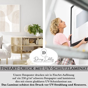 Op de afbeelding: Een witte en bruine abstracte geometrische poster met een zwarte lijst wordt opgehangen aan een witte muur. De poster is gedrukt op dik, hoogwaardig papier en gelamineerd met een UV-beschermende coating. "FINEART-DRUCK MIT UV-SCHUTZLAMINAT" staat in zwarte tekst onderaan de afbeelding. "Unsere Fotoposter drucken wir in FineArt-Aufl&ouml;sung auf ein 250 g/m&sup2; schweres Fotopapier und laminieren dies mit einem glasklaren UV-Schutzlaminat aus. Das Laminat sch&uuml;tzt den Druck vor UV-Strahlung und Kratzern." staat in zwarte tekst onder de titel.