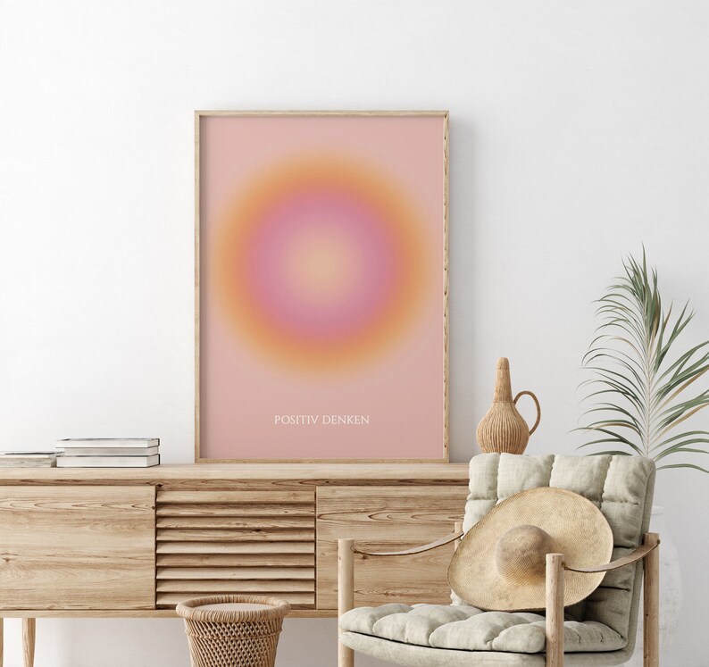 May include: A framed print with a pink and orange gradient circle in the center. The text "POSITIV DENKEN" is printed at the bottom of the print.