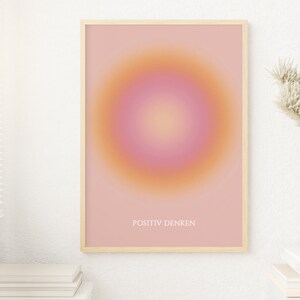 May include: A framed print with a pink and orange gradient circle in the center. The text "POSITIV DENKEN" is printed in white at the bottom of the print.