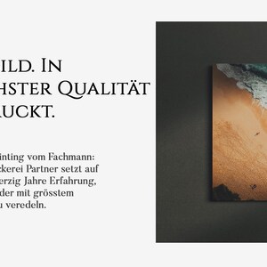 Op de afbeelding: Een ingelijste foto van een strandsc&egrave;ne met turquoise water, witte golven en een zandstrand met mensen die erop lopen. De tekst "IHR BILD. IN H&Ouml;CHSTER QUALIT&Auml;T GEDRUCKT." staat onder de afbeelding.