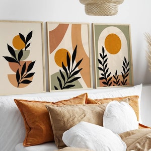 Op de afbeelding: Drie abstracte kunstprints met een minimalistisch ontwerp met zwarte silhouetten van bladeren en takken tegen een achtergrond van beige, groen en oranje.