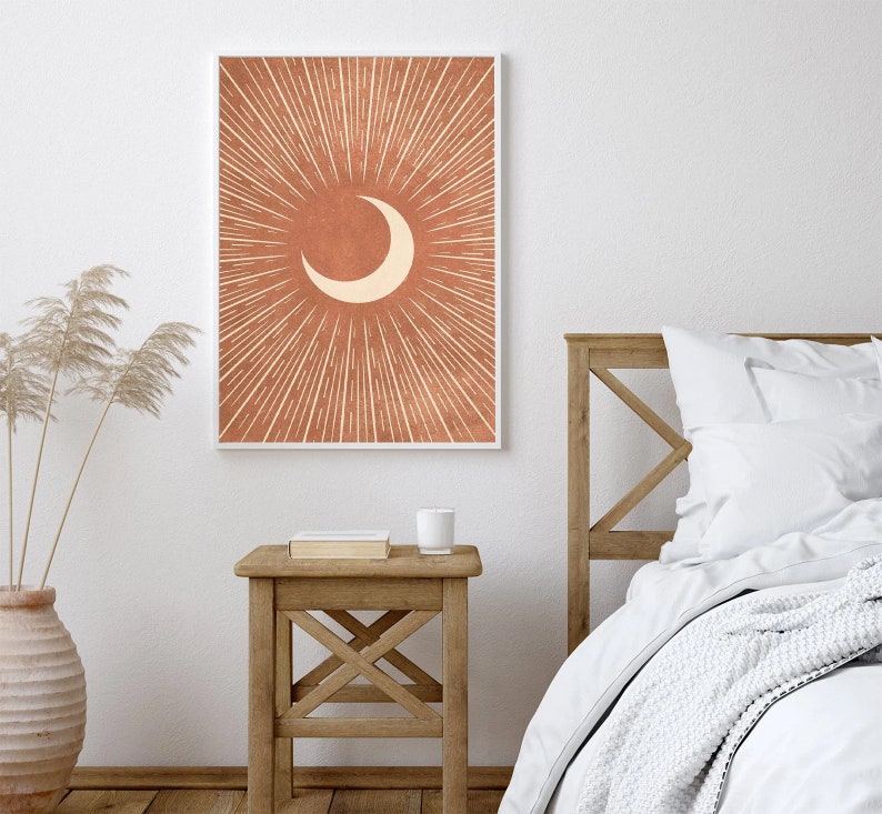 Puede incluir: Una impresi&oacute;n digital de una luna creciente en silueta blanca sobre un fondo terracota con l&iacute;neas radiantes.