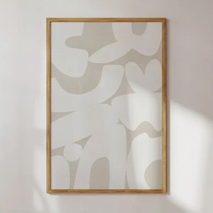 Op de afbeelding: Een ingelijst abstract drukwerk met een beige achtergrond en witte organische vormen. De lijst is gemaakt van natuurlijk hout.