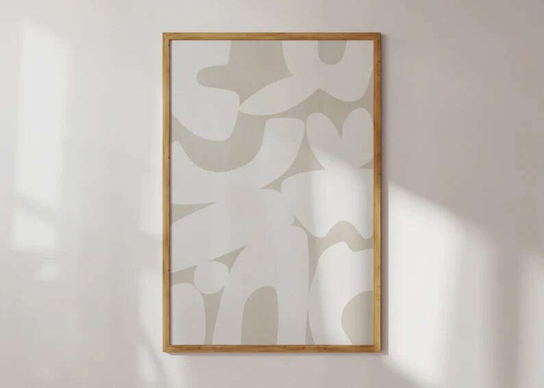 Op de afbeelding: Een ingelijst abstract drukwerk met een beige achtergrond en witte organische vormen. De lijst is gemaakt van natuurlijk hout.