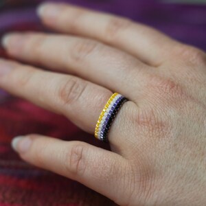 Könnte beinhalten: Ein Perlenring mit gelben, weißen und violetten Perlen, der die Non-Binary-Pride-Flagge darstellt.
