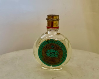 May include: A small, clear glass bottle of Blue & Gold Eau de Cologne Double Strength. The bottle has a gold cap and a green and gold label with the text "Blue & Gold Eau de Cologne Double Strength" and "4711."