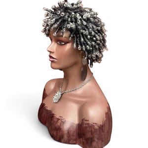 May include: A mannequin head featuring short, dark hair styled in tight, coiled ringlets with silver-toned highlights. The mannequin wears a silver-toned chain necklace with a textured, leaf-shaped pendant and a long, dark, oval-shaped drop earring.