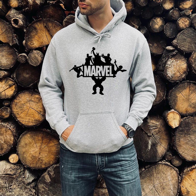 May include: A gray hooded sweatshirt with a black graphic print of Marvel superheroes. The graphic features the Marvel logo and silhouettes of several superheroes, including Iron Man, Captain America, Thor, and Hulk.