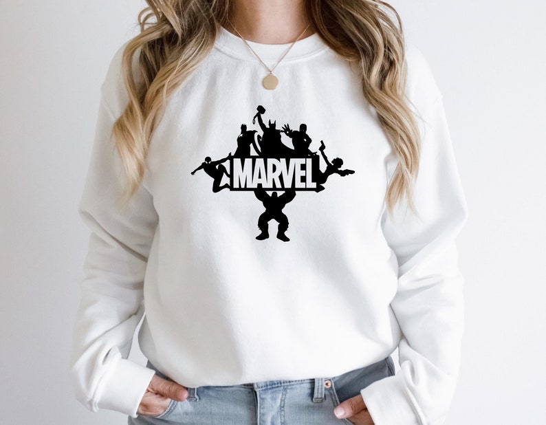 May include: White sweatshirt with a black silhouette of Marvel characters holding up the word "MARVEL".