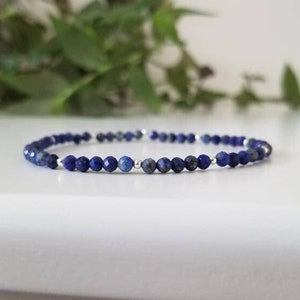 May include: A delicate blue lapis lazuli beaded bracelet with silver spacer beads.