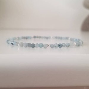May include: A delicate bracelet made with light blue gemstone beads and silver accents.