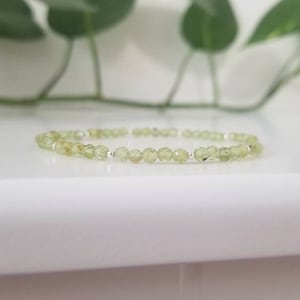 May include: A delicate bracelet made with light green gemstone beads and silver spacers.