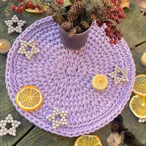 Puede incluir: Un camino de mesa de crochet morado con un diseño en forma de estrella. El camino de mesa está decorado con estrellas de madera y rodeado de velas, fruta seca y rodajas de naranja.