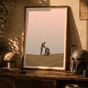 Op de afbeelding: Een ingelijste verticale kunstdruk met een minimalistische illustratie van de Star Wars-personages C-3PO en R2-D2 die op een zanderig woestijnlandschap onder een bleke lucht staan. De print zit in een eenvoudige houten lijst op een houten ondergrond.