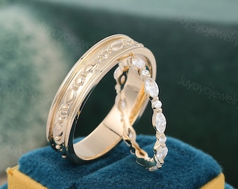 May include: A pair of gold wedding bands with a decorative design. The band on the left has a textured pattern and the band on the right is set with small diamonds.