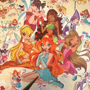 Op de afbeelding: Een verzameling gestanste stickers met diverse geanimeerde feeënfiguren met kleurrijke vleugels, verschillende kapsels en outfits. De stickers tonen personages met grote ogen in dynamische houdingen, waaronder oranje, blond, bruin en zwart haar.