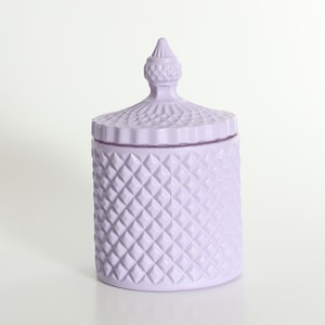 May include: A lavender glass candle jar with a diamond pattern and a decorative lid.