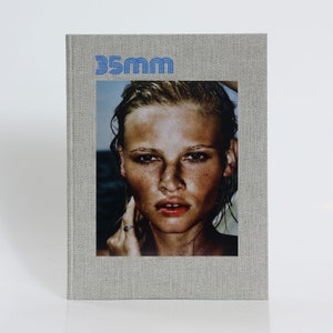 May include: A grey book with the title "35mm" printed in blue on the front cover. The cover features a photograph of a woman's face with freckles.