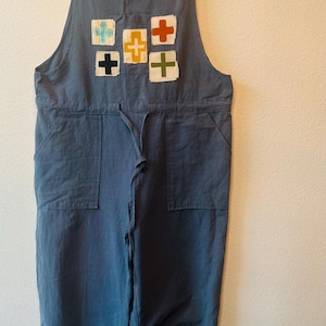 Może przedstawiać: Zestaw trzech ceramicznych kubków z nakrapianym, matowym wykończeniem. Kubki są w odcieniach kremu, jasnoszarym i ciemnoszarym. Każdy kubek ma prosty, nowoczesny design i zaokrąglony uchwyt.