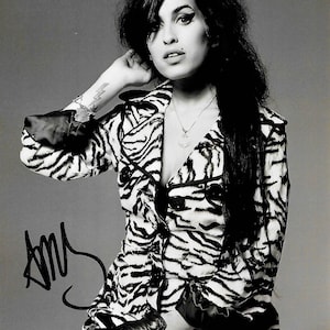 Puede incluir: Fotografía en blanco y negro de una persona con una chaqueta con estampado de cebra abotonada. La persona tiene el pelo oscuro y lleva un collar. La imagen está firmada con el nombre "Amy".