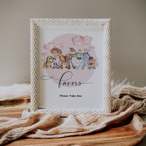 K&ouml;nnte beinhalten: Ein gerahmtes Schild mit einem wei&szlig;en, strukturierten Rahmen. Das Schild zeigt eine Aquarellillustration von Charakteren aus Toy Story, vor einem rosa Hintergrund mit Wolken. Das Wort "Favors" ist in Schreibschrift geschrieben, darunter "Please Take One".