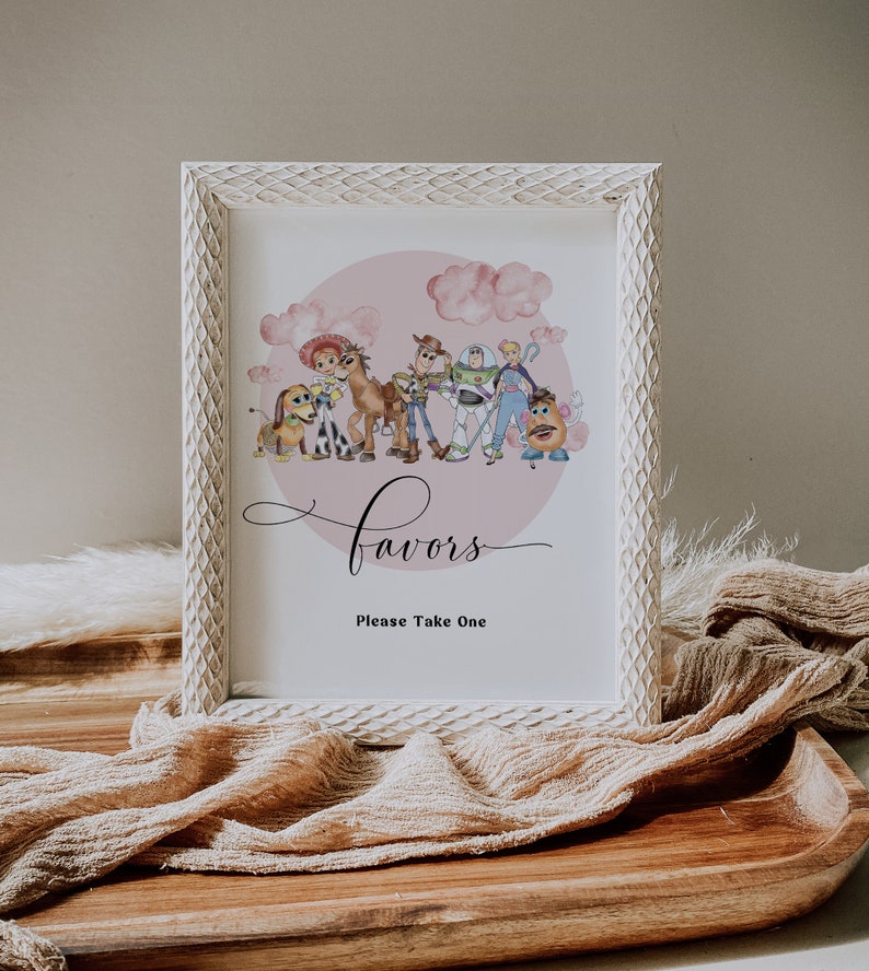 K&ouml;nnte beinhalten: Ein gerahmtes Schild mit einem wei&szlig;en, strukturierten Rahmen. Das Schild zeigt eine Aquarellillustration von Charakteren aus Toy Story, vor einem rosa Hintergrund mit Wolken. Das Wort "Favors" ist in Schreibschrift geschrieben, darunter "Please Take One".