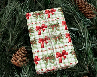 May include: A rectangular gift box wrapped in white and light green checkered paper featuring red bows, green bows, and the repeating red text "Love, Mom & Dad" with small red hearts, tied with thin brown twine.