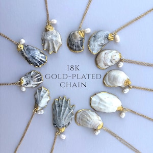 May include: A collection of necklaces featuring oyster shell pendants with 18K gold-plated edges and small white pearls, suspended from 18K gold-plated chains. The text 18K GOLD-PLATED CHAIN is centered among the arranged jewelry pieces.