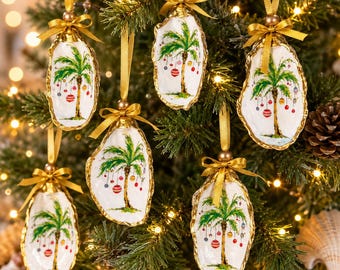 May include: Six oyster shell ornaments featuring hand-painted palm trees decorated with colorful Christmas baubles. Each shell is topped with a gold ribbon bow and a matching gold hanging loop, creating a festive coastal holiday display.