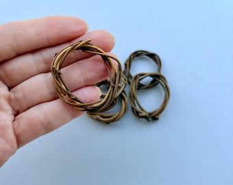 May include: A set of small, circular rings crafted from thin, intertwined brown twigs. Each ring features a rustic, natural texture with varying shades of brown, created by the overlapping and winding of individual woody stems into a continuous loop.