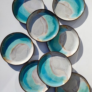 K&ouml;nnte beinhalten: Satz von acht Keramiktellern mit einer blauen, wei&szlig;en und braunen Glasur. Die Teller haben ein einzigartiges, marmoriertes Design.