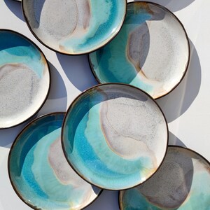 K&ouml;nnte beinhalten: Ein Set aus sechs Keramik-Dinnertellern mit einer blauen, wei&szlig;en und braunen Glasur. Die Teller haben ein einzigartiges, marmoriertes Design.