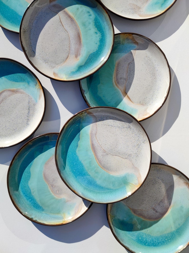 K&ouml;nnte beinhalten: Ein Set aus sechs Keramik-Dinnertellern mit einer blauen, wei&szlig;en und braunen Glasur. Die Teller haben ein einzigartiges, marmoriertes Design.