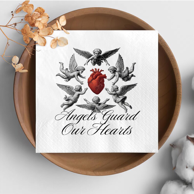 May include: White square napkin with a design featuring cherubic angels surrounding a red heart. The text "Angels Guard Our Hearts" is written in elegant script below the angels. The napkin is placed in a wooden bowl.