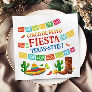 May include: White paper napkin with a colorful Cinco de Mayo Fiesta design. The design includes the text "Cinco de Mayo Fiesta Texas-Style!" with illustrations of a sombrero, cactus, and cowboy boot.