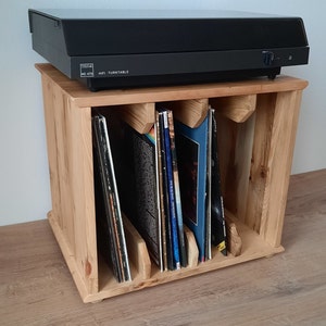 May include: A wooden record storage unit with three compartments for vinyl records. A black turntable sits on top of the unit. The turntable has the text "HIFI TURNTABLE" and "MC 470" printed on it.