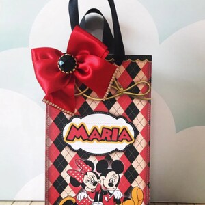 Peut inclure: Sac cadeau rouge et noir avec un n&oelig;ud rouge et une poign&eacute;e noire. Le sac a un motif &agrave; carreaux et repr&eacute;sente Mickey et Minnie Mouse. Le sac est personnalis&eacute; avec le nom "Maria".