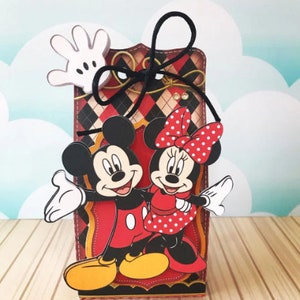 Peut inclure: Une bo&icirc;te &agrave; carreaux rouges et noirs avec un ruban noir. Mickey Mouse et Minnie Mouse sont sur le devant de la bo&icirc;te. Mickey porte un short rouge et des chaussures jaunes. Minnie porte une robe rouge &agrave; pois blancs et des chaussures rouges.