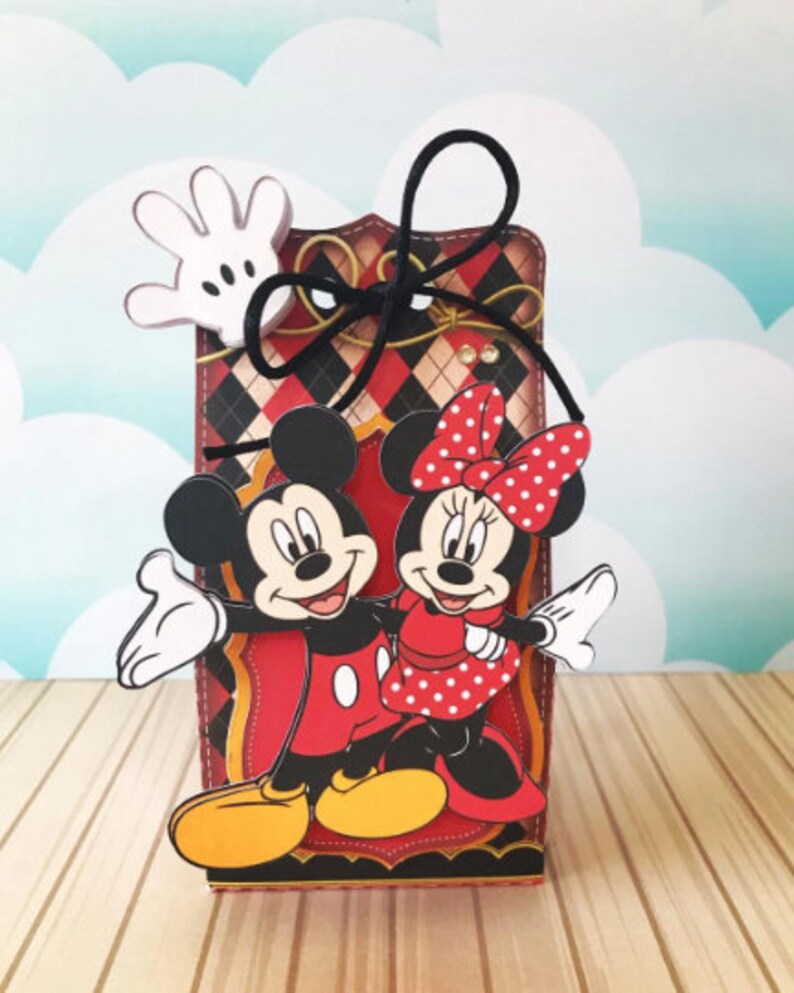 Peut inclure: Une bo&icirc;te &agrave; carreaux rouges et noirs avec un ruban noir. Mickey Mouse et Minnie Mouse sont sur le devant de la bo&icirc;te. Mickey porte un short rouge et des chaussures jaunes. Minnie porte une robe rouge &agrave; pois blancs et des chaussures rouges.