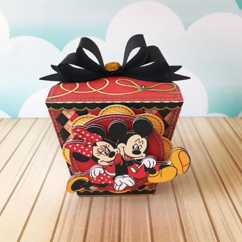 Peut inclure: Une bo&icirc;te cadeau rouge et noire avec un n&oelig;ud noir. La bo&icirc;te pr&eacute;sente une image de dessin anim&eacute; de Mickey Mouse et Minnie Mouse.