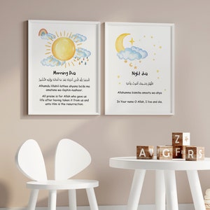 Puede incluir: Dos impresiones enmarcadas con ilustraciones de acuarela de un sol y una luna. Las impresiones tienen texto árabe y traducciones al inglés de oraciones islámicas para la mañana y la noche. Las impresiones están colgadas en una pared rosa claro sobre una mesa blanca con bloques de madera que deletrean "AGFRS" y "Z". Un juguete de peluche de jirafa está de pie en el suelo junto a la mesa.