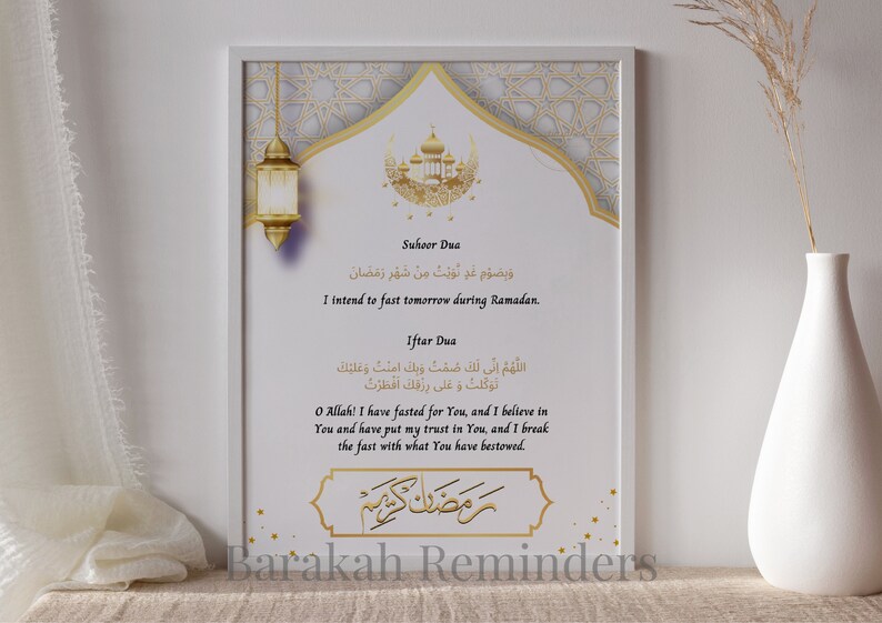 May include: A white framed print with gold accents featuring Arabic text and an English translation of a prayer for Ramadan. The text reads "Suhoor Dua" and "I intend to fast tomorrow during Ramadan." The text also reads "Iftar Dua" and "O Allah! I have fasted for You, and I believe in You and have put my trust in You, and I break the fast with what You have bestowed." The print also features a crescent moon and a star.