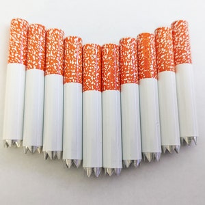 May include: Ten white and orange cigarette-shaped objects with a pointed end. The objects are arranged in a semi-circle shape.