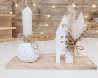 Snow crystal candle holder with candle, house and dried flowers on wood