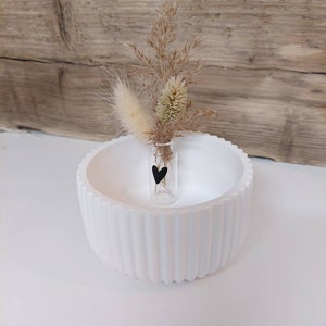 Puede incluir: Un cuenco de cer&aacute;mica blanco con un peque&ntilde;o jarr&oacute;n de vidrio que contiene hierbas secas y una pegatina de coraz&oacute;n negro. El jarr&oacute;n est&aacute; en el centro del cuenco.